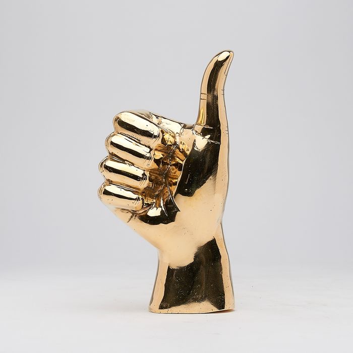 Hand met duim omhoog in gepolijst messing